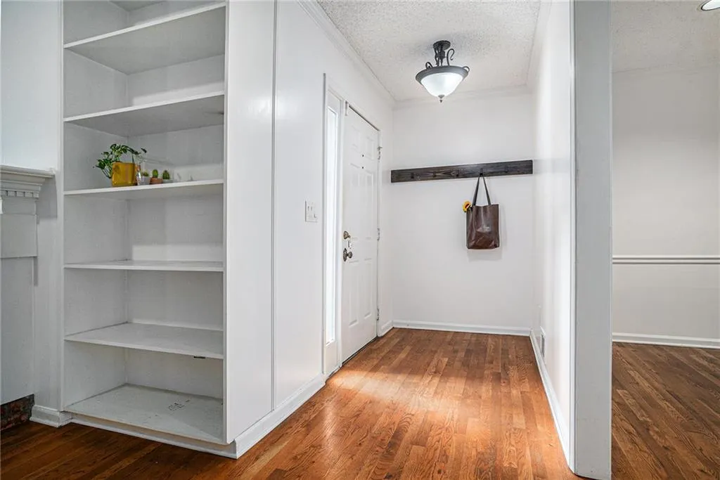 Hall featuring dark wood-style flooring, a textured ceiling, and ornamental molding Hall featuring dark wood-style flooring, a textured ceiling, and ornamental molding