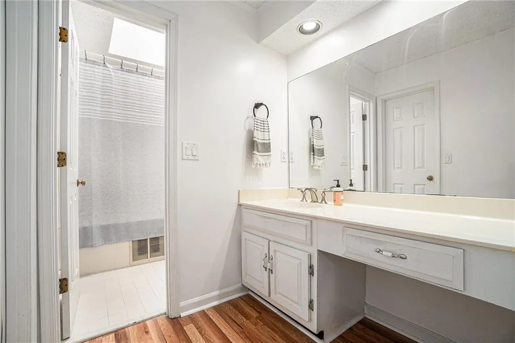 Full bath featuring vanity, dark wood-style floors, and a shower with shower curtain Full bath featuring vanity, dark wood-style floors, and a shower with shower curtain