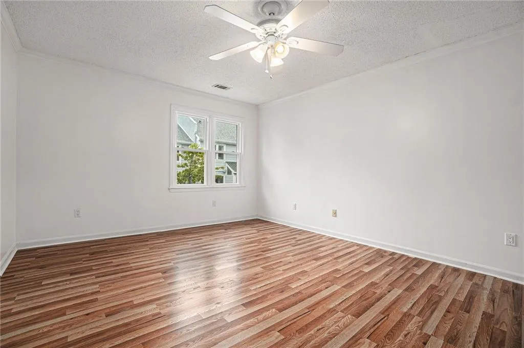 Spare room with crown molding, light wood-style floors, a textured ceiling, and ceiling fan Spare room with crown molding, light wood-style floors, a textured ceiling, and ceiling fan