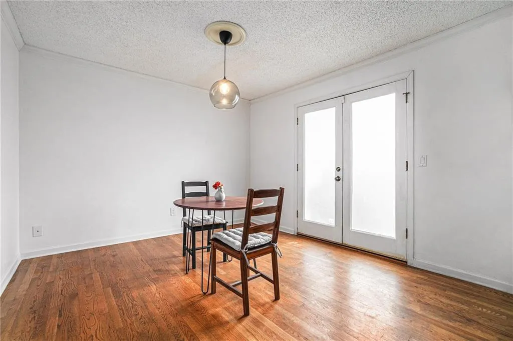 Dining space featuring crown molding, a textured ceiling, wood finished floors, and french doors Dining space featuring crown molding, a textured ceiling, wood finished floors, and french doors