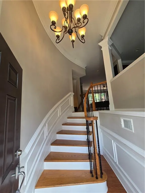 Stairs featuring ornamental molding, wood finished floors, and a decorative wall