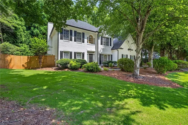 Traditional-style exterior with white brick facade, black shutters, and a dark shingled roof