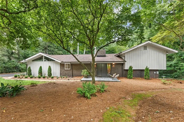 Mid-century modern residence featuring a dark brick exterior and white board-and-batten siding