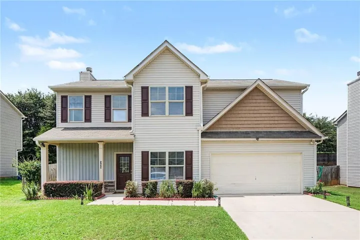 Two-story residence featuring light-colored siding, a covered front porch, and a two-car garage
