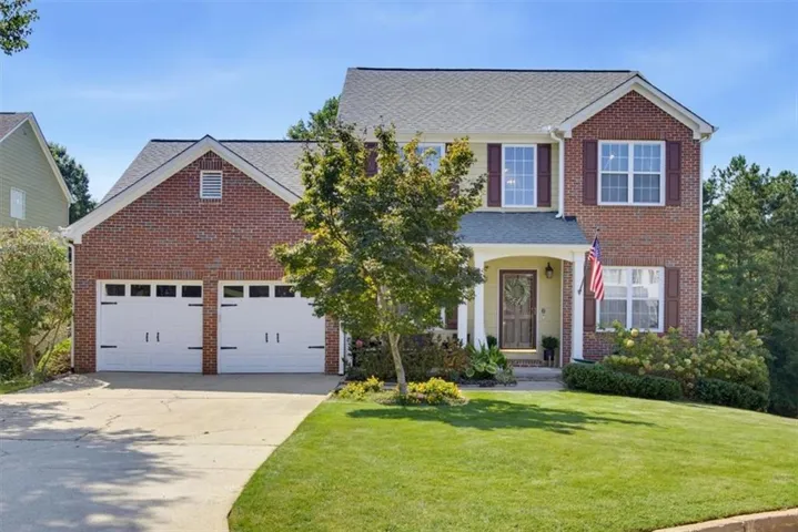 Brick and siding exterior with a covered entry, two-car garage, and mature landscaping