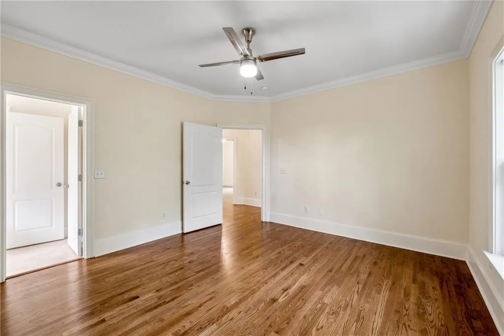 Unfurnished bedroom with ceiling fan, wood-type flooring, and ornamental molding
