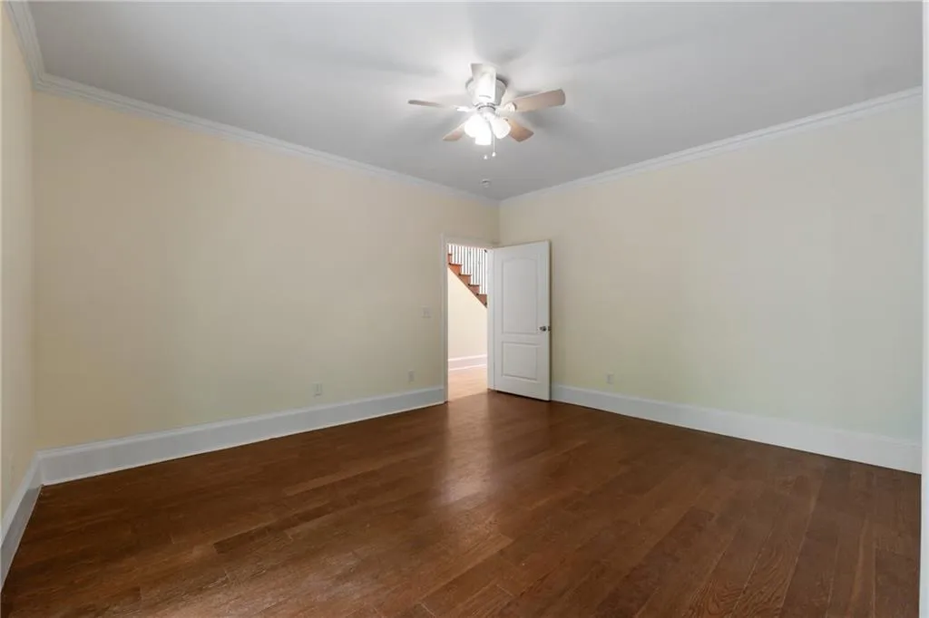 Empty room with ceiling fan, dark hardwood / wood-style floors, and crown molding