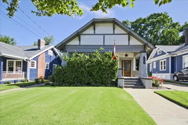 Craftsman-style facade with a covered porch, wood-paneled front door, concrete porch steps, and a well-maintained lawn
