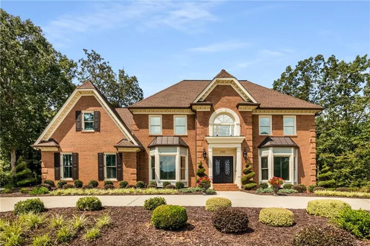 Colonial house featuring brick siding, roof with shingles, and french doors