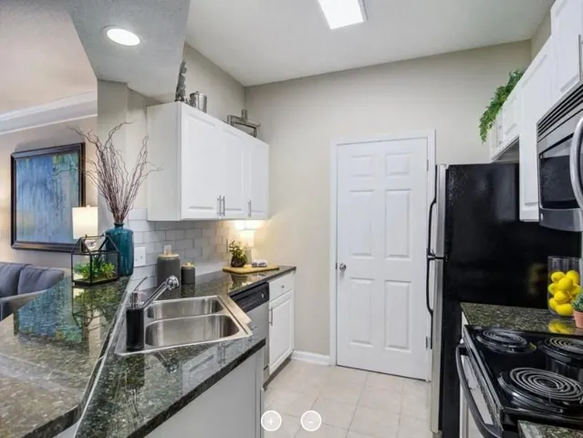 Kitchen with sink, appliances with stainless steel finishes, decorative backsplash, and white cabinetry
