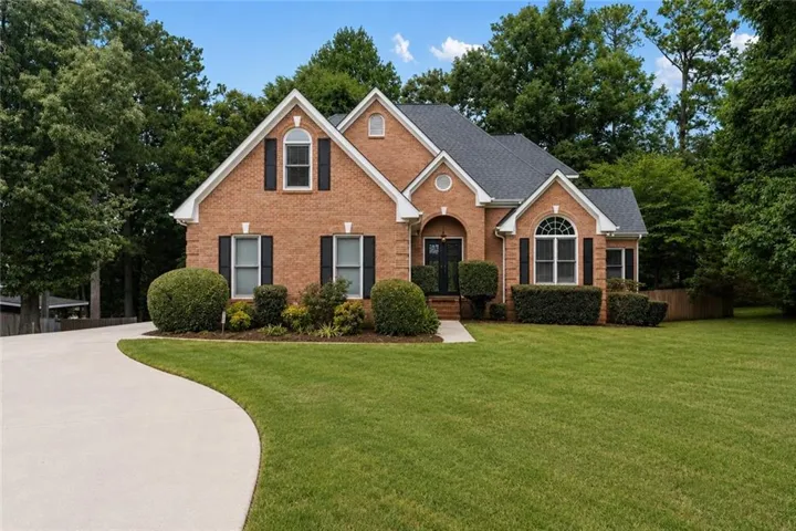 Brick exterior with a dark shingle roof, featuring multiple gables and arched windows