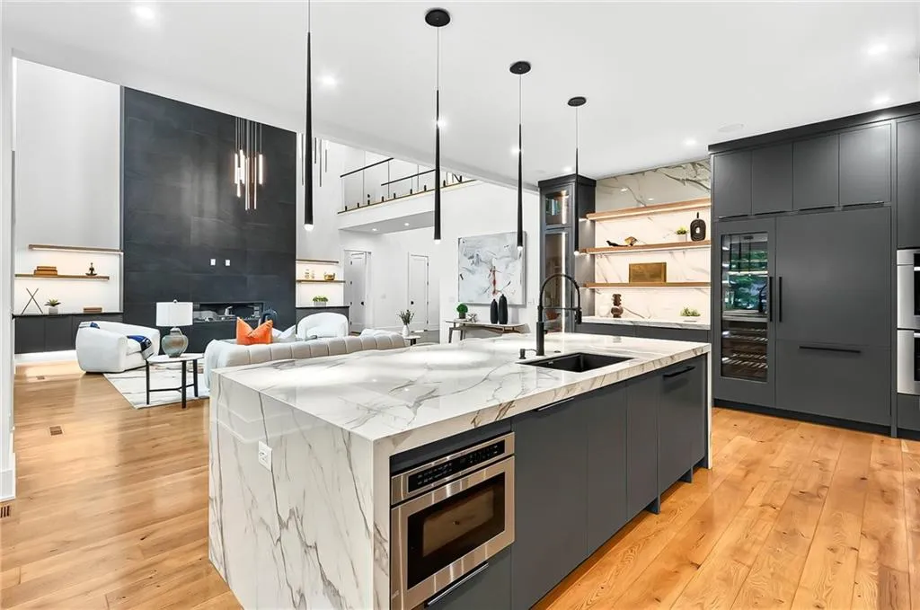 Kitchen featuring modern cabinets, a sink, light wood-style floors, a kitchen island with sink, and hanging light fixtures