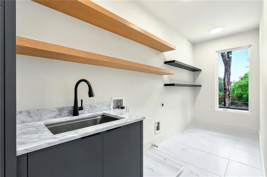 Laundry room featuring light marble finish flooring, hookup for an electric dryer, hookup for a washing machine, baseboards, and cabinet space