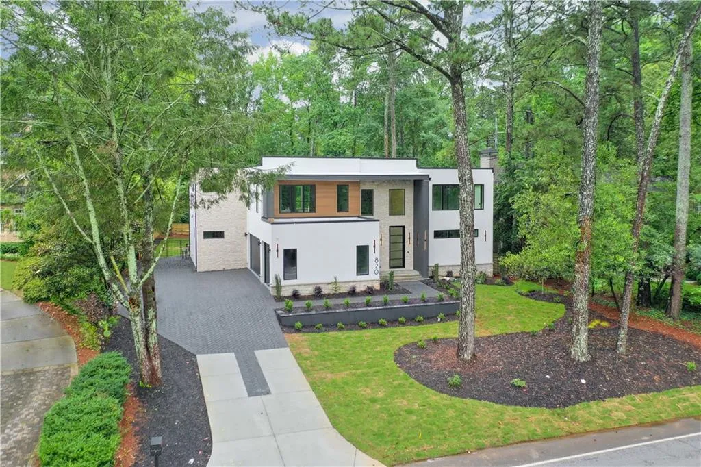 Modern home with driveway, stucco siding, a front yard, a garage, and view of scattered trees