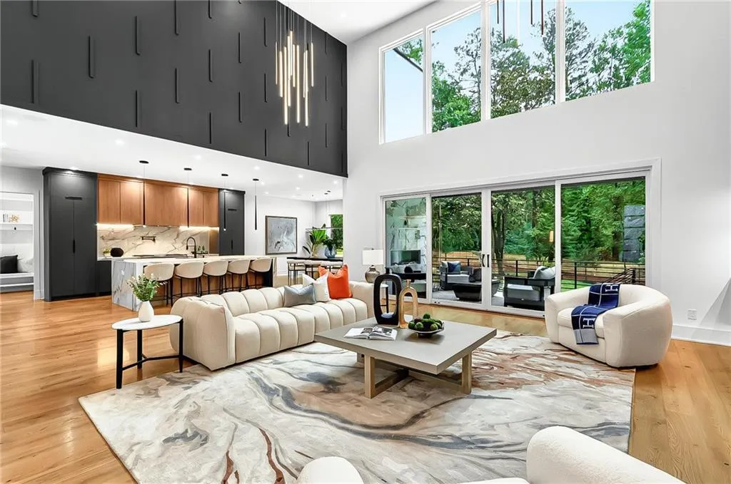 Living area featuring light wood-style flooring, plenty of natural light, and a towering ceiling
