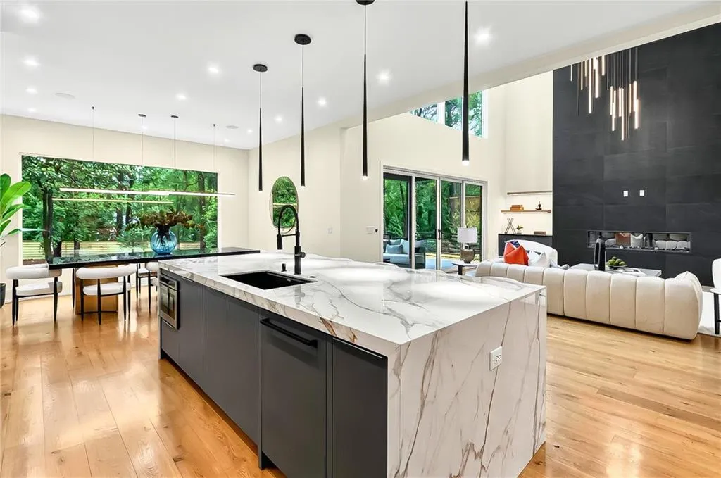 Kitchen featuring a sink, a spacious island, light wood-type flooring, modern cabinets, and a high ceiling