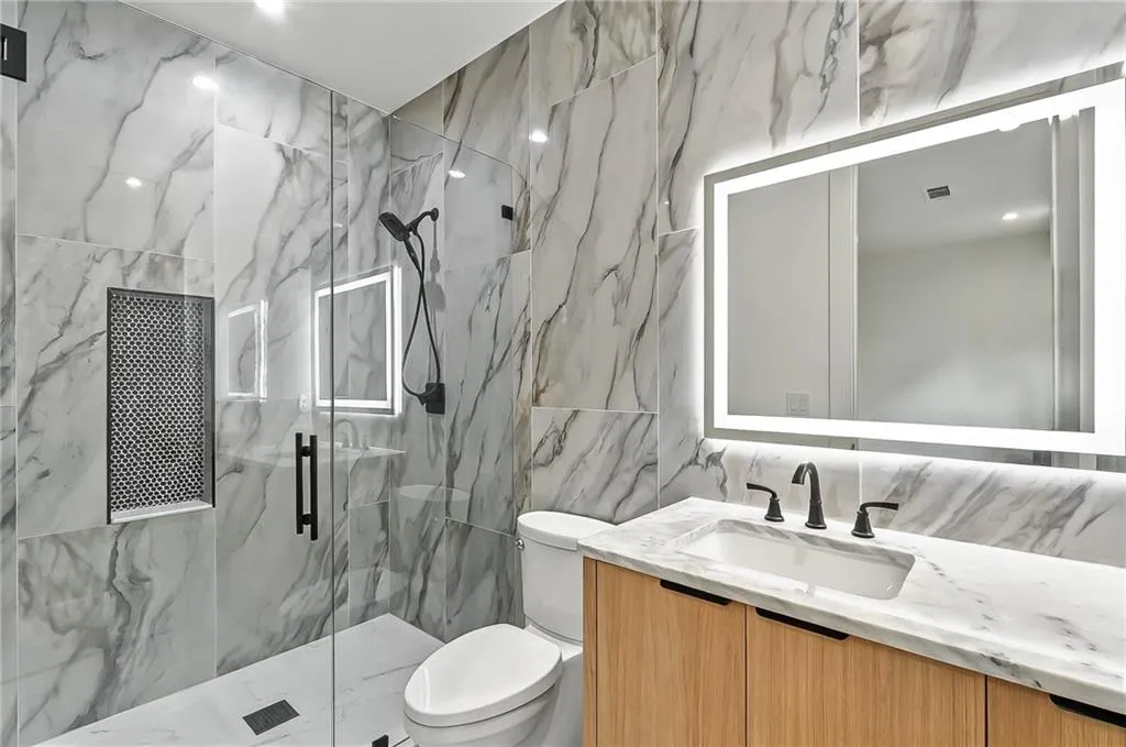 Full bath with tile walls, a marble finish shower, vanity, and toilet