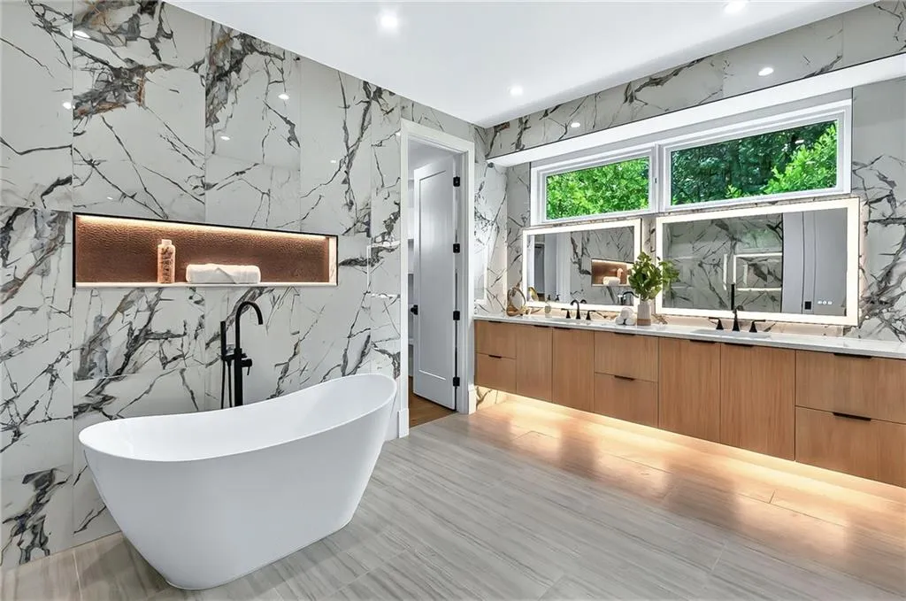 Bathroom featuring double vanity, a freestanding bath, stone wall, and recessed lighting