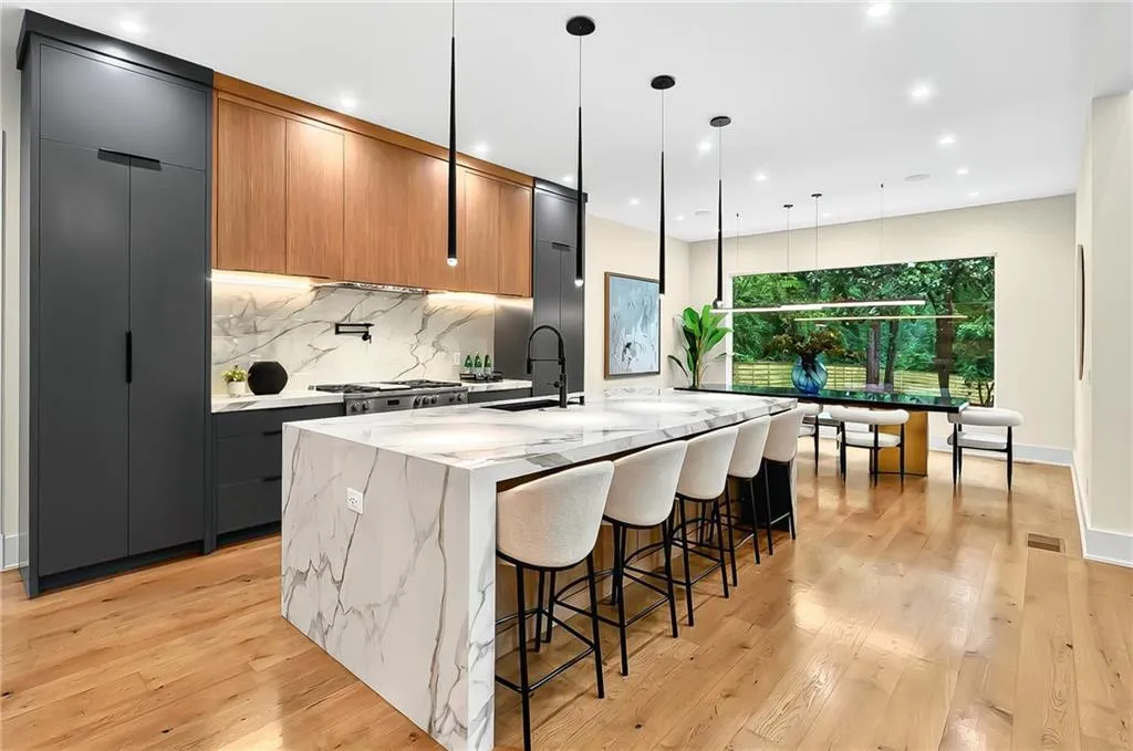 Kitchen with modern cabinets, a large island with sink, light wood finished floors, backsplash, and recessed lighting