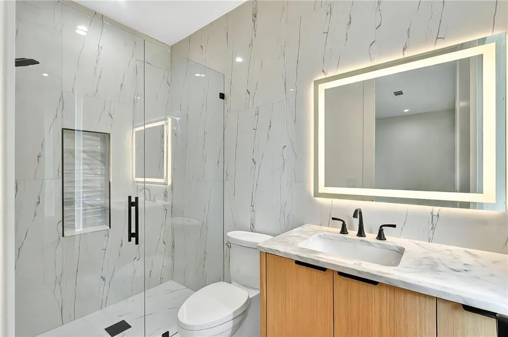 Full bathroom featuring tile walls, vanity, a marble finish shower, and toilet