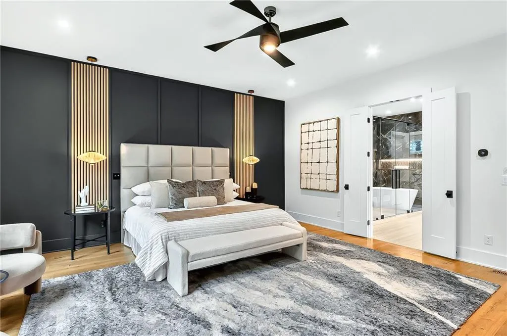 Bedroom featuring wood finished floors, baseboards, a ceiling fan, and ensuite bathroom
