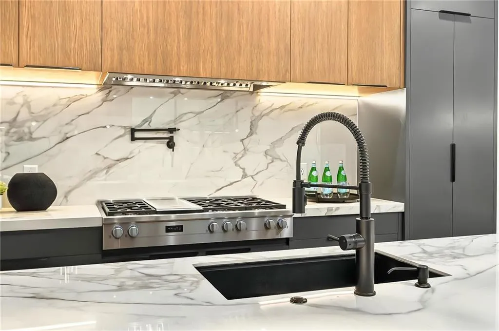Kitchen with decorative backsplash, light stone countertops, modern cabinets, a sink, and stove
