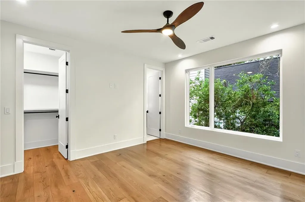 Unfurnished bedroom with a walk in closet, light wood finished floors, baseboards, recessed lighting, and ceiling fan