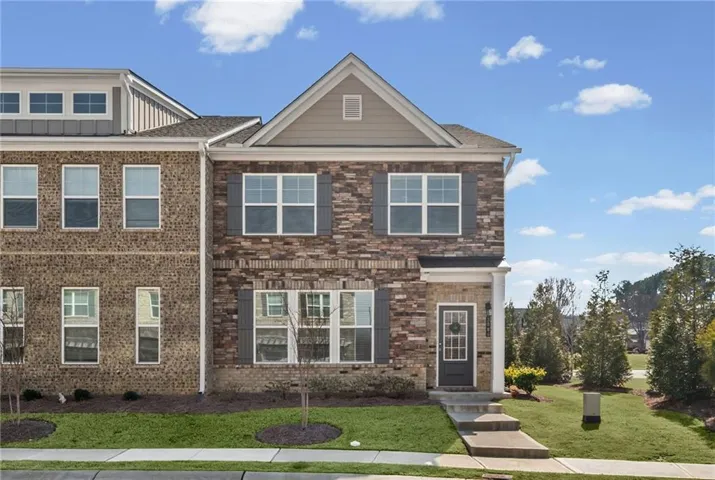 Brick and stone facade with a gable roof, featuring a covered entry and functional shutters