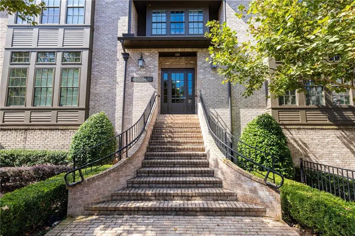 Brick exterior featuring a multi-story design, arched brick entryway, iron handrails, and a prominent front door with glass panels
