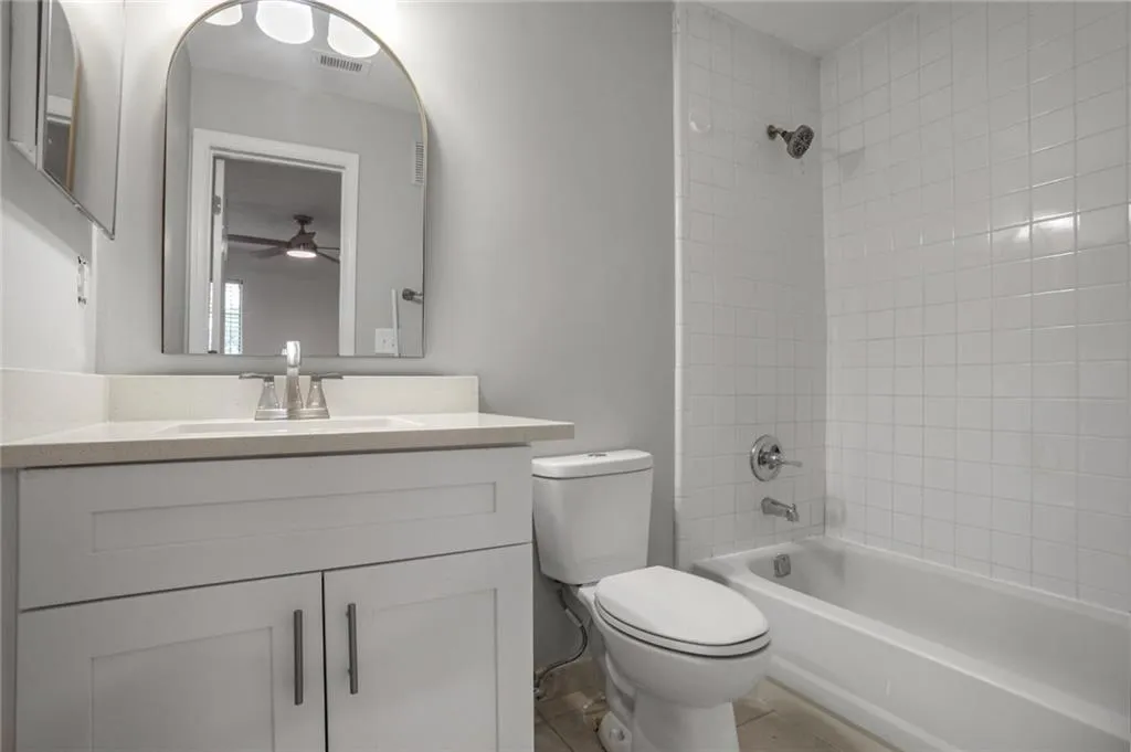 Bathroom with toilet, ceiling fan, shower / tub combination, vanity, and tile patterned floors