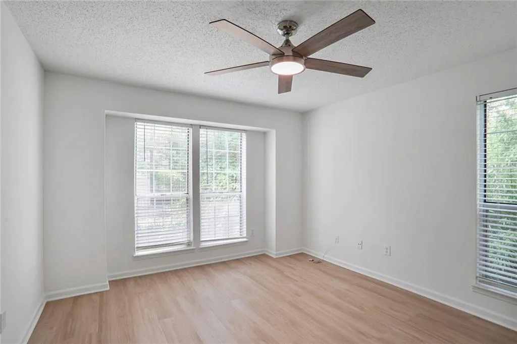 Spare room with light wood-type flooring, a textured ceiling, a ceiling fan, and baseboards