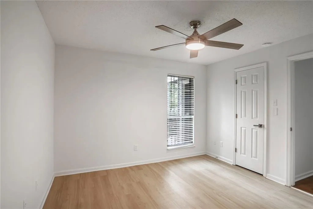 Empty room featuring light wood finished floors, a ceiling fan, baseboards, and a textured ceiling