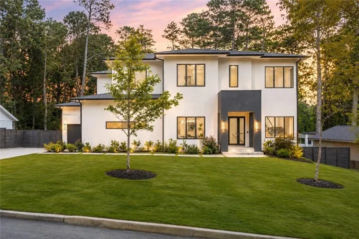 Modern architectural facade with a contrasting dark entrance, extensive landscaping, and a broad driveway