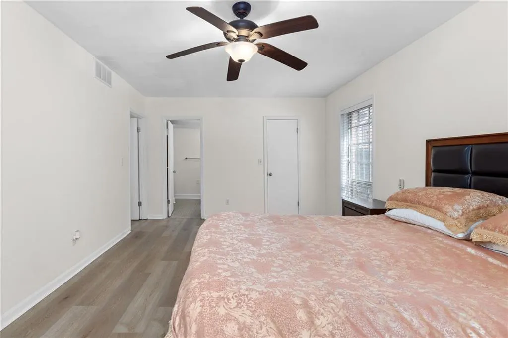Bedroom with light wood-style floors, a ceiling fan, and ensuite bath