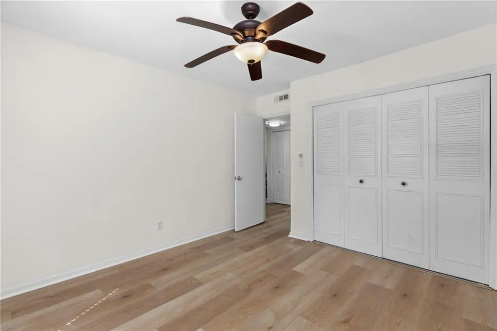 Unfurnished bedroom featuring light wood-style floors, ceiling fan, and a closet