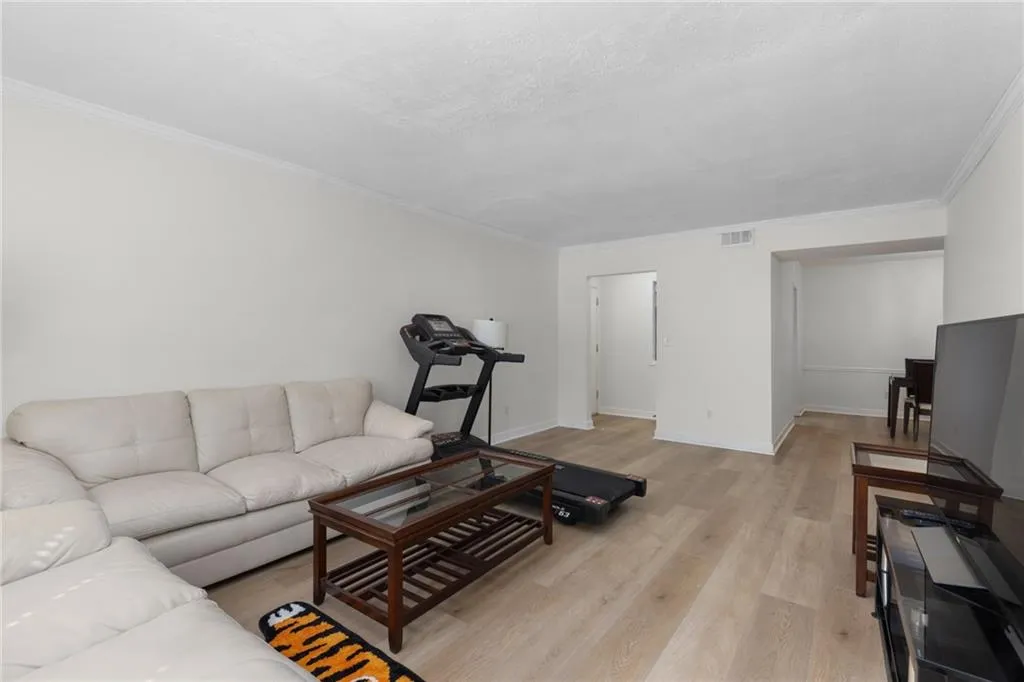 Living room featuring ornamental molding, light wood finished floors, and a textured ceiling