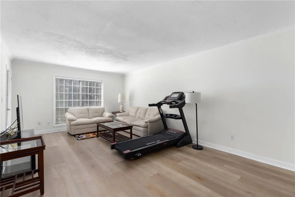 Exercise room featuring ornamental molding, a textured ceiling, and light wood-type flooring