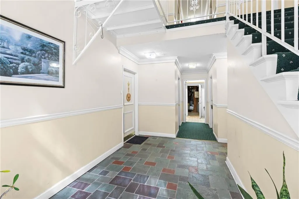 Hall featuring stone tile flooring and crown molding