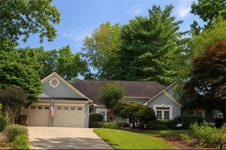 Ranch-style residence featuring a light blue facade, two-car garage, and a dark roof
