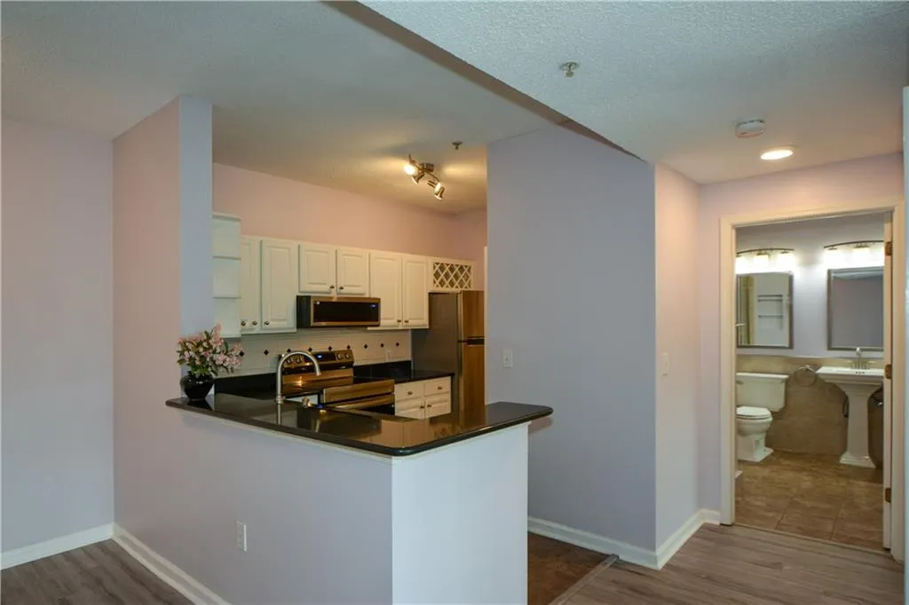 Kitchen featuring dark wood-type flooring, appliances with stainless steel finishes, a peninsula, a textured ceiling, and decorative backsplash