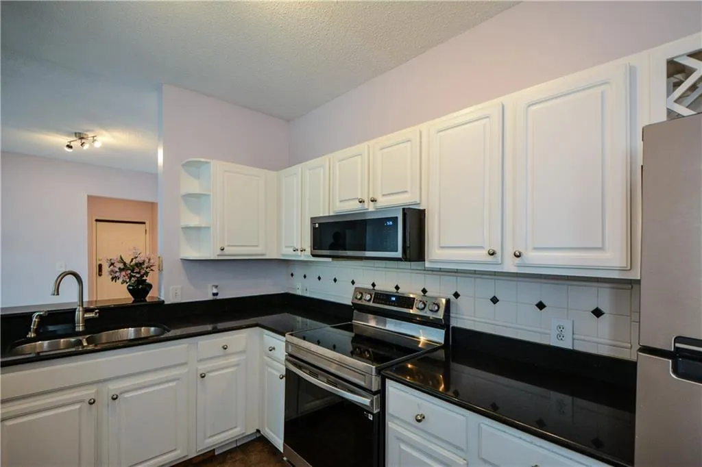 Kitchen featuring stainless steel appliances, tasteful backsplash, white cabinets, open shelves, and a textured ceiling