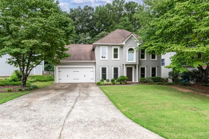 Two-story residence featuring a light gray exterior, an attached two-car garage, and a concrete driveway