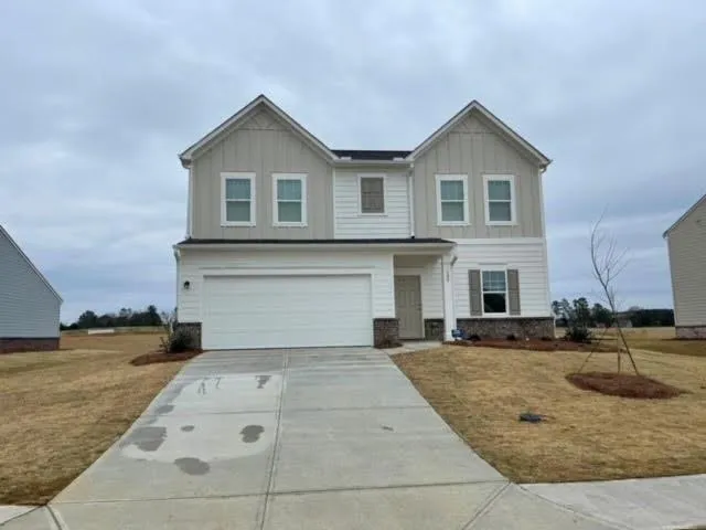 Two-story residence featuring a two-car garage, stone and siding exterior, and a concrete driveway