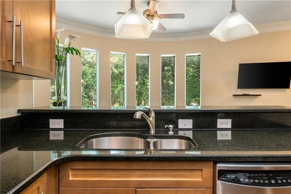 Curved breakfast bar with dark countertops, wood cabinetry, and an undermount sink
