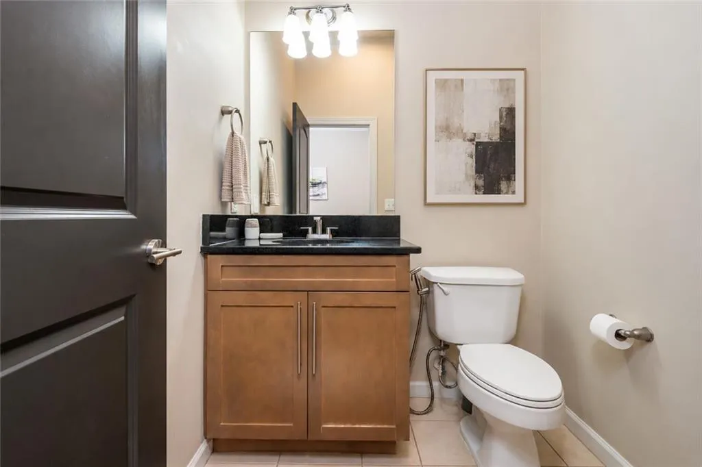 Powder room featuring a wood-finish vanity with a dark countertop, undermount sink, and a wall-mounted light fixture