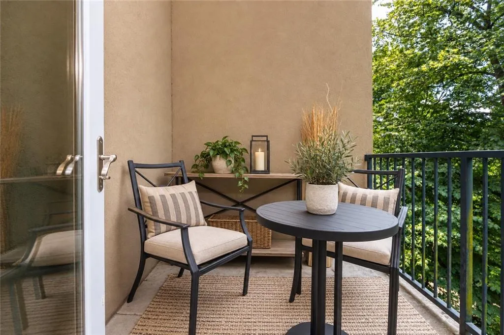 Private balcony featuring stucco exterior, a black metal railing, and a glass door with a brushed nickel handle