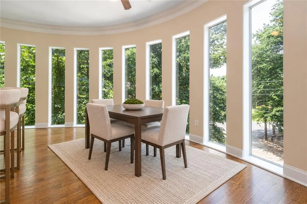 Curved wall featuring multiple floor-to-ceiling windows, wood-finish flooring, and a ceiling fan