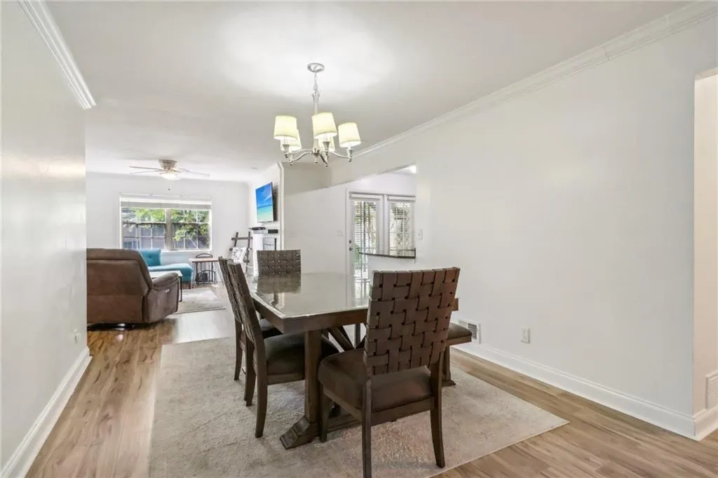 Dining area featuring ceiling fan with notable chandelier, light hardwood / wood-style flooring, and ornamental molding Dining area featuring ceiling fan with notable chandelier, light hardwood / wood-style flooring, and ornamental molding