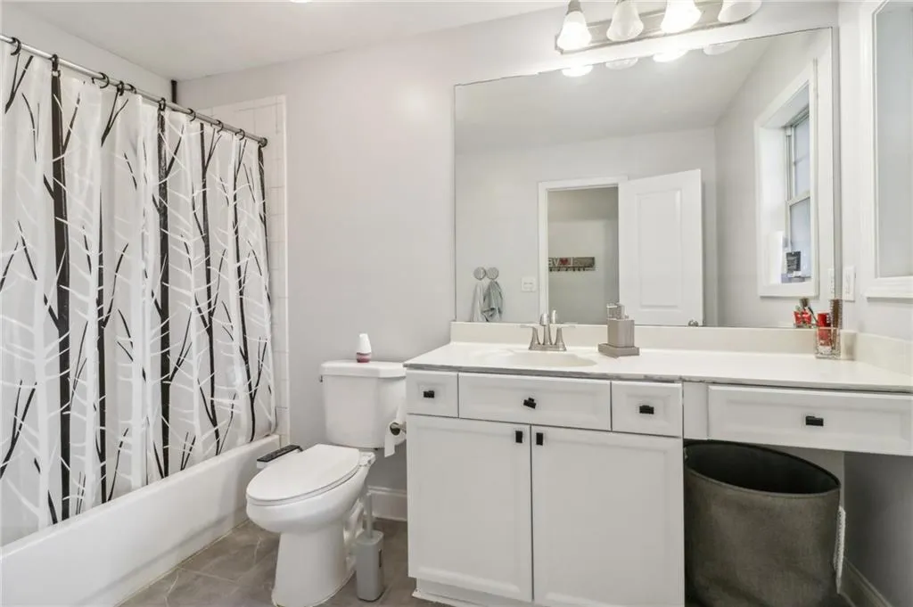 Full bathroom featuring shower / tub combo, tile patterned flooring, toilet, and vanity Full bathroom featuring shower / tub combo, tile patterned flooring, toilet, and vanity