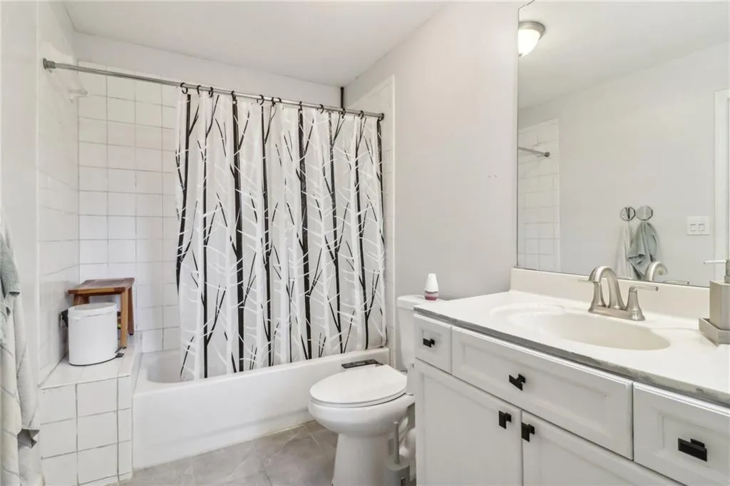 Full bathroom with vanity, tile patterned floors, shower / tub combo, and toilet Full bathroom with vanity, tile patterned floors, shower / tub combo, and toilet